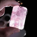 Aries purple agate pendant held against light to show the carving