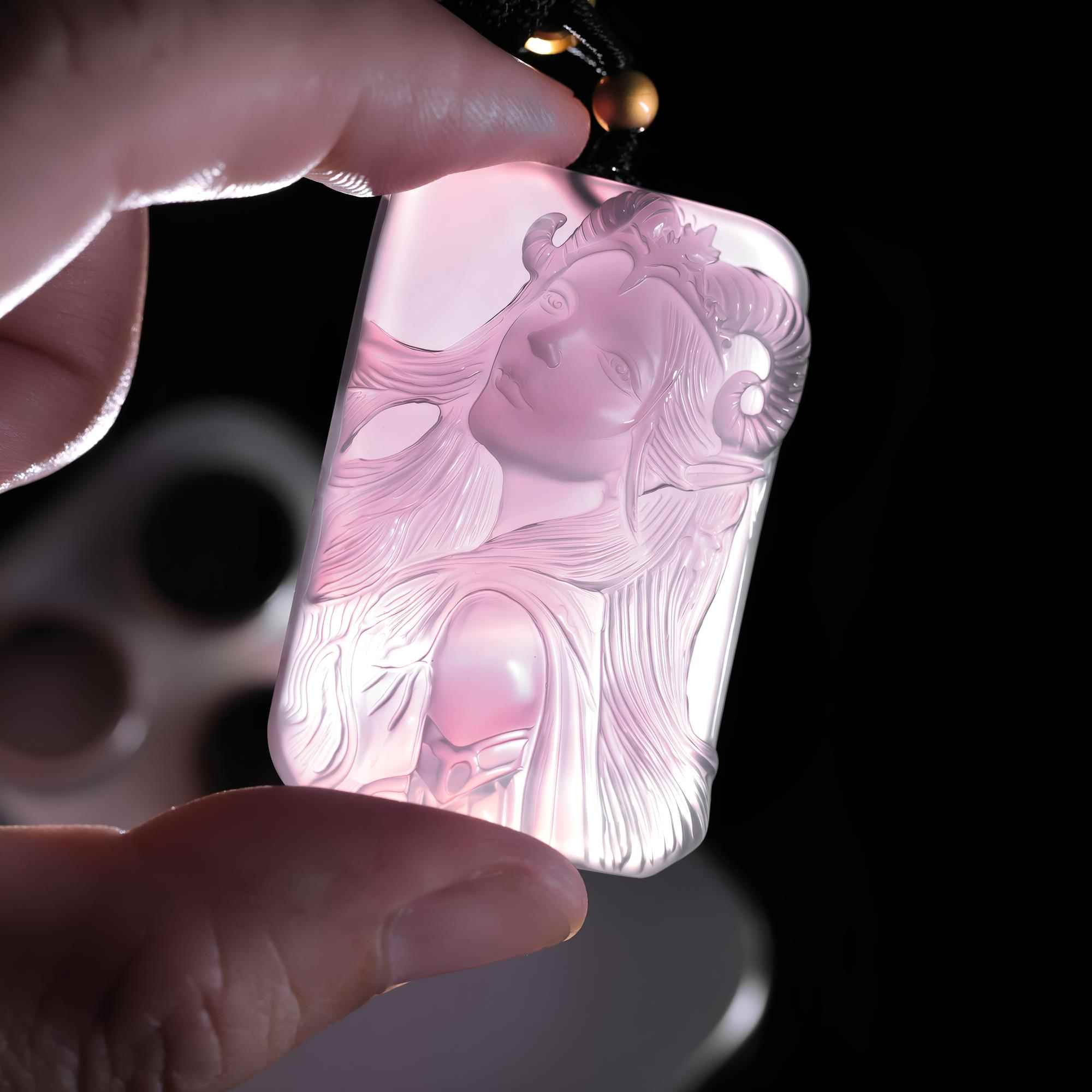 Aries purple agate pendant held against light to show the carving