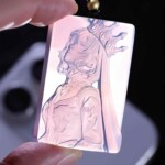 Leo purple agate pendant held against light to show the carving