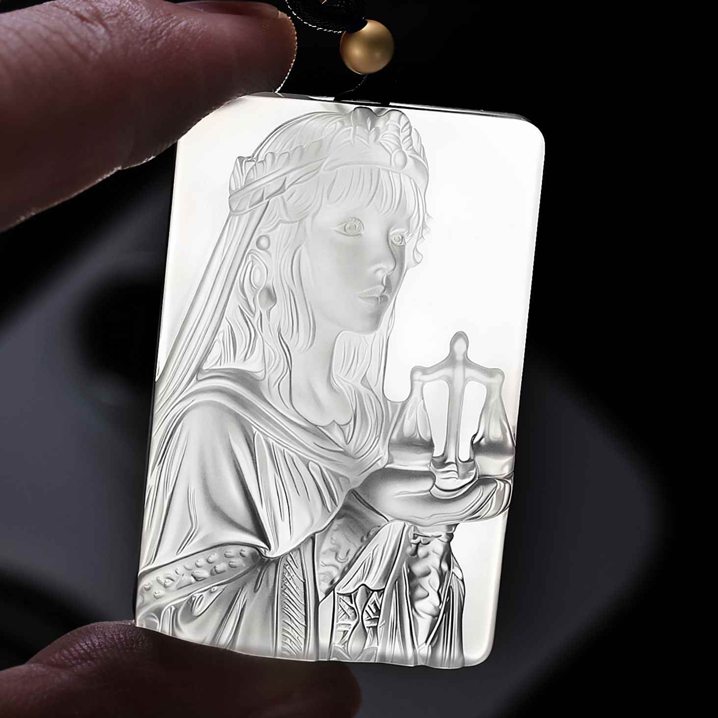 Libra white agate pendant held against light to show the carving