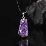 Raw amethyst necklace with a purple crystal surface and silver-tone setting on a black cord
