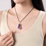 Raw amethyst necklace worn with a cream top, showing the pendant scale