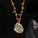 Raw green fluorite necklace in knotted brown cord with green accents against a dark background