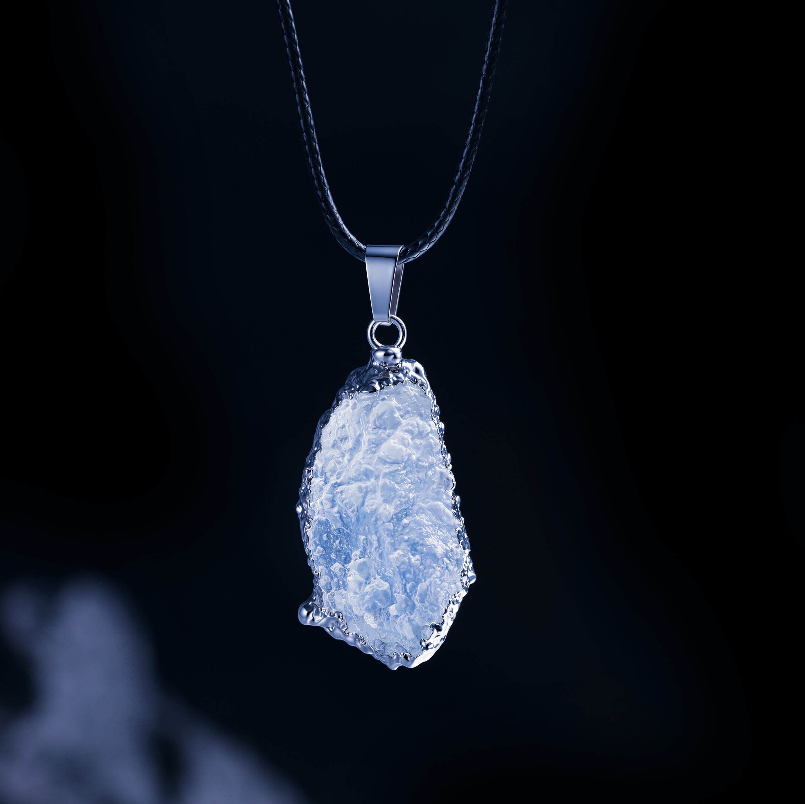 Raw aquamarine necklace showing textured blue stone on a black cord
