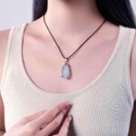 Raw aquamarine necklace worn on a black cord with a light top