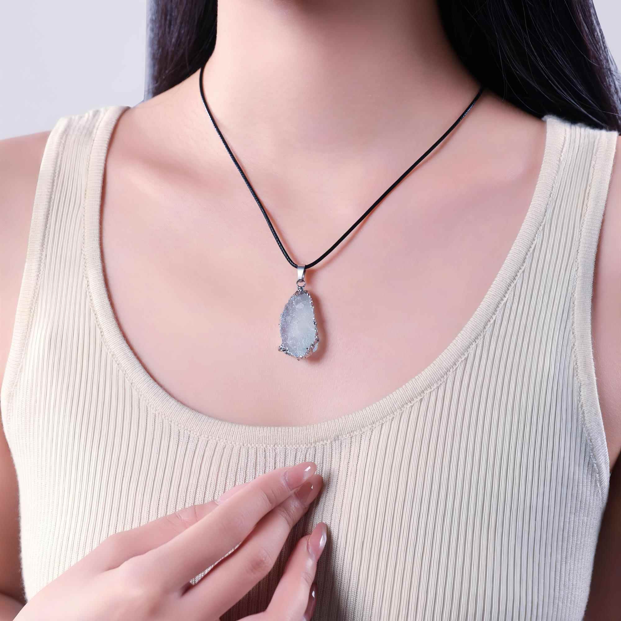 Raw aquamarine necklace worn on a black cord with a light top